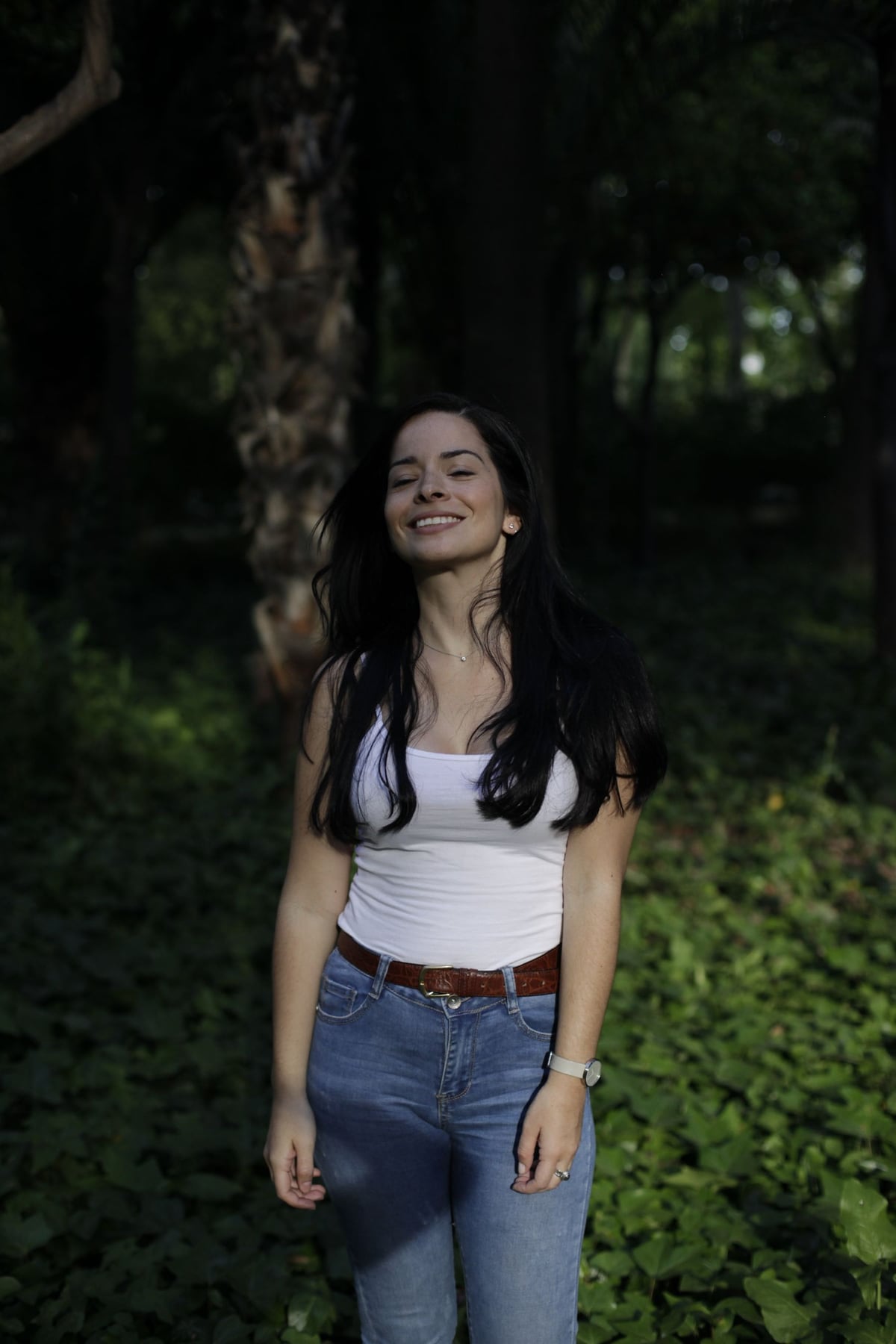 A smiling woman standing among trees in a Dublin woodland